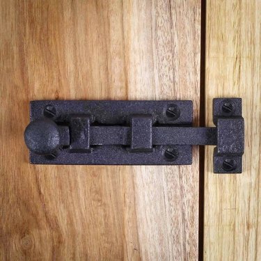 A black latch door lock on a wooden door