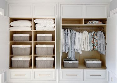 Large linen closet with baskets, hanging quilts.