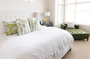 bedroom featuring an olive green couch and white bedding