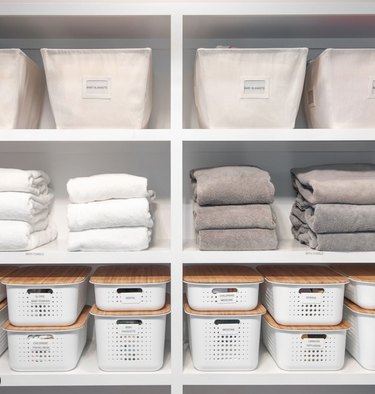 Linen closet with white bins and towels.