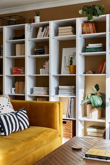 mustard yellow sofa with tan walls and built-in bookshelf