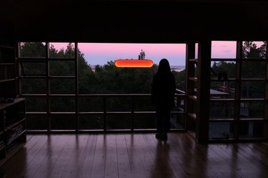 room at dusk with person in silouhette standing near window with solar light