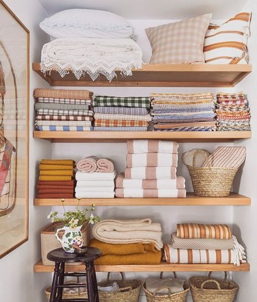 Linen cubby with sheets, towels, pillows, baskets.