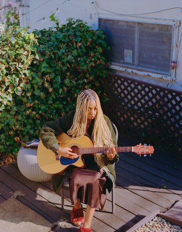 person sitting outside with guitar