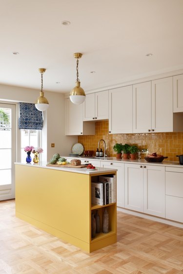 Kitchen with wood floors and a yellow island.