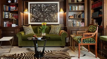 Home office with olive green couch and wood paneling