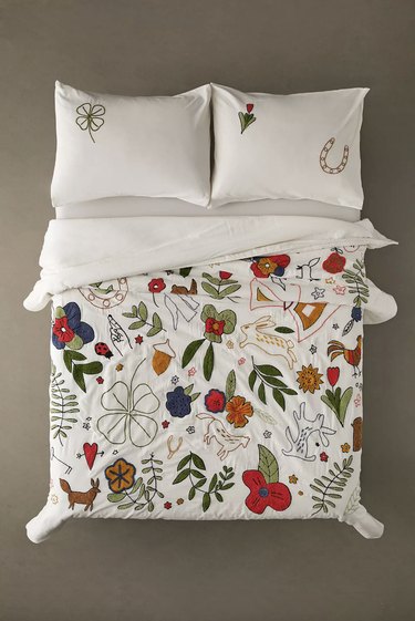 Quilt with colorful tufted illustrations and embroidery on a white quilt