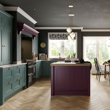 Kitchen with teal cabinets and purple island, black stainless range, herringbone wood floors.