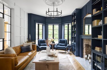 Den with wood floors and a navy accent wall.