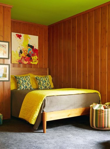 lime green ceiling in bedroom with panelled walls and yellow soft furnishings