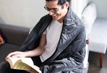 Man reading wrapped in weighted blanket.