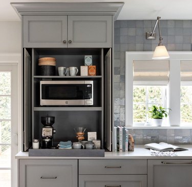 Gray kitchen with microwave, coffee station.