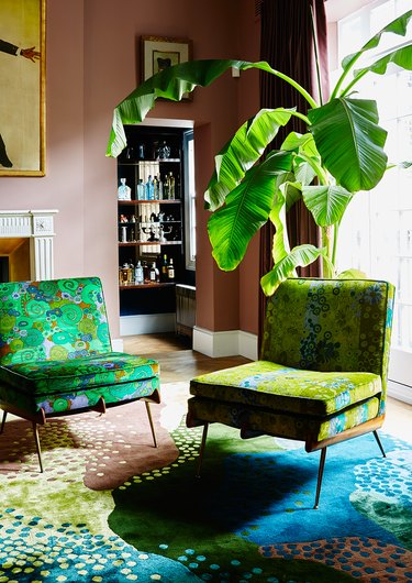 lime green patterned occasional chairs in clay brown room with plants