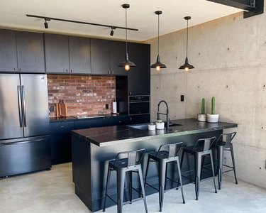 Kitchen with black cabinets, black refrigerator and gray floors.