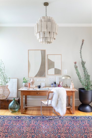 gray home office with pendant light, purple and blue rug, wooden desk with two abstract art pieces hanging above it