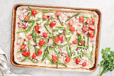 Partially baked pie crust with vegetables and feta cheese