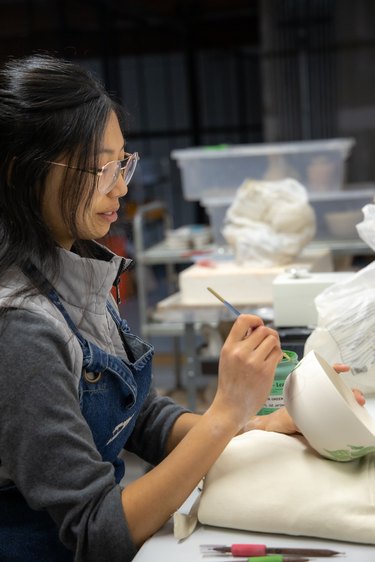 person painting on a ceramic piece