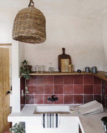 Rustic kitchen with maroon backsplash and stone countertops.