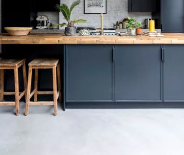 Kitchen with dark gray cabinets, gray floors, butcher block counters.
