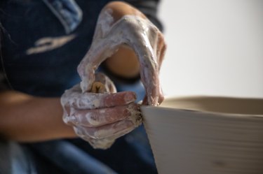 person working with pottery on wheel