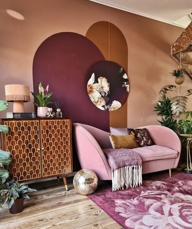 Living room with maroon accent wall and pink couch.