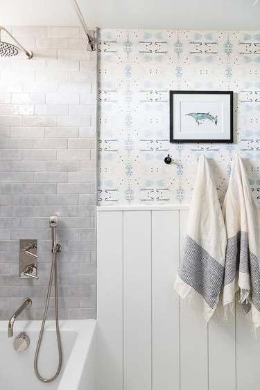 Coastal vibe basement bathroom with blue motif wallpaper and gray shower tiles