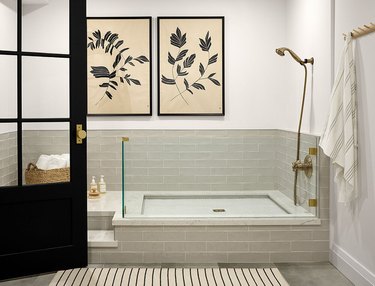 Gray tile dog bath in a basement with a black door