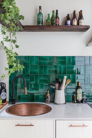 white kitchen with bronze sink and green glazed tile backsplash