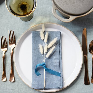place setting with blue napkin and dried stem