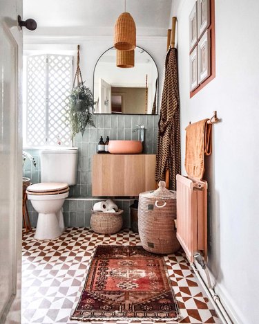 Boho bathroom in white, sage green, muted oranges and reds with painted brick red and white geometric floor