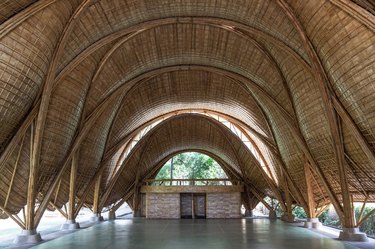A large, high-ceiling room inside a giant bamboo building with light coming up from spaces between the walls and floor.