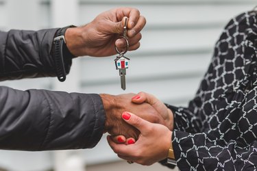 people shaking hands over home sale with home key