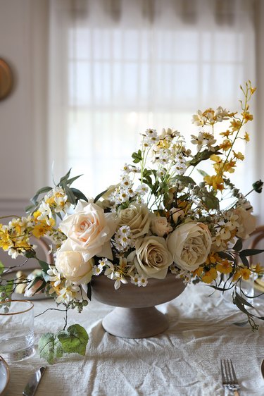 DIY faux spring wildflower centerpiece in compote bowl on table