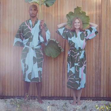 Two people wearing IKEA's new kimono featuring a pink, green, and blue rhubarb leaf print.