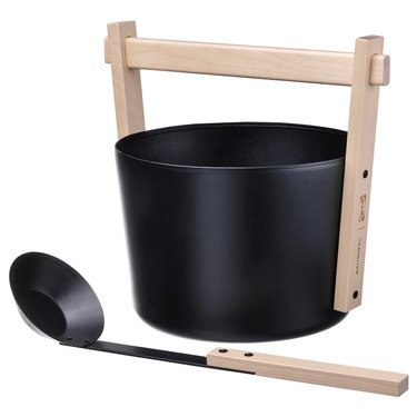 A black sauna bucket with a light wood handle and a matching ladle.