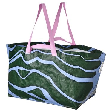 A large tote bag with a dark green and light blue pattern and two light pink top handles.