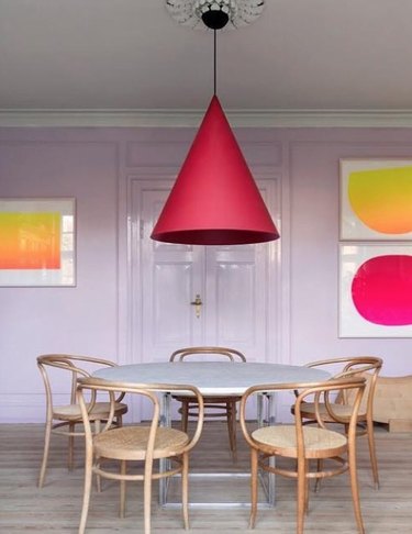 Dining room with lilac walls, red pendant lamp, art.