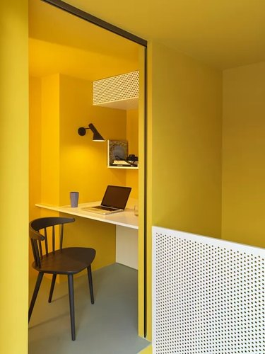 minimalist yellow home office with built-in desk and black desk chair