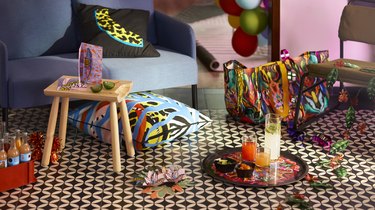 Pillows, a tote bag, and servingware from IKEA's IKEA's ÖMSESIDIG collection on a black and white patterned floor.