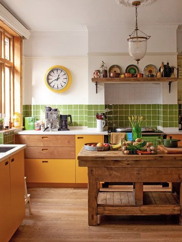 Kitchen with yellow cabinets and green backsplash.