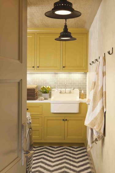 laundry room with yellow cabinets, beige walls, and bronze fixtures