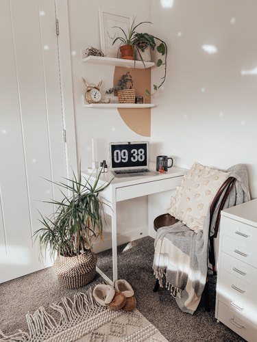 small home office with white floating shelves and painted half circle