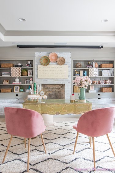 pastel basement office with built-in shelves and pink chairs