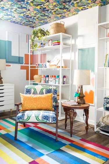 colorful basement office with wallpapered ceiling and chair with orange pillow