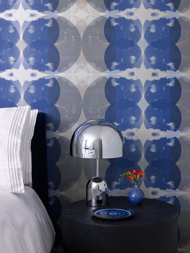 bedroom with cobalt blue patterned wallpaper and silver table lamp