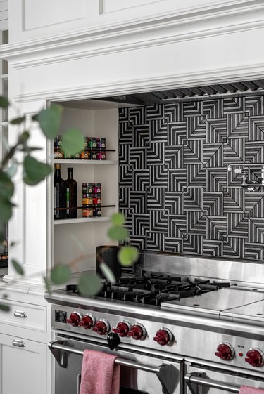 kitchen with black and silver backsplash, white cabinets, silver oven