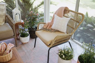 Wicker chair on patio with pink blanket and pillow