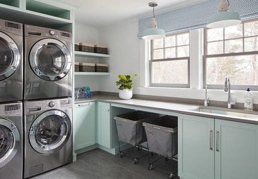 laundry room with mint green cabinets, silver hardware, and silver washer/dryer units
