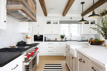 Rustic kitchen with custom reclaimed wood hood, white cabinets.
