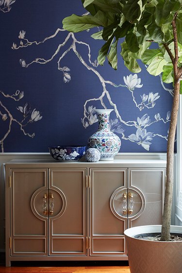 silver cabinet in front of navy blue wallpaper with silver print